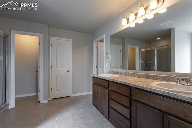 bathroom with walk in shower, tile patterned flooring, and vanity