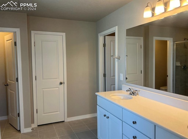 bathroom with vanity, a shower with door, toilet, and tile patterned floors