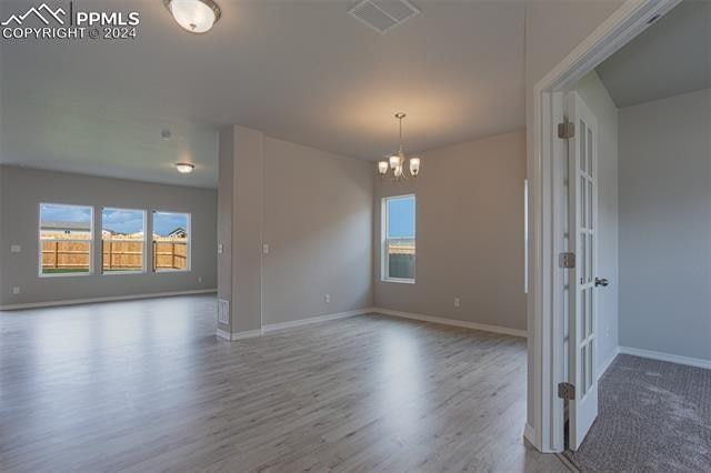 empty room featuring wood-type flooring and a chandelier