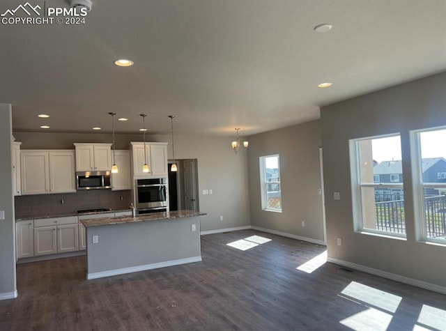 kitchen featuring white cabinetry, pendant lighting, stainless steel appliances, and a kitchen island with sink