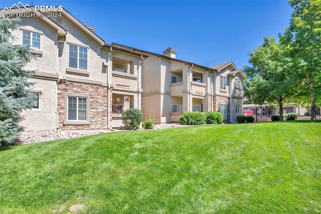 rear view of property featuring a balcony and a lawn