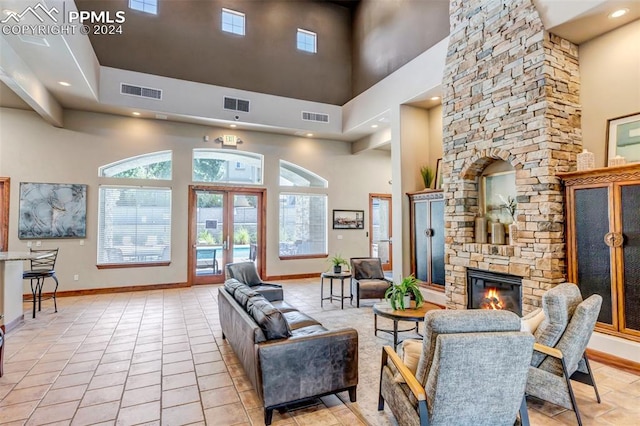 tiled living room with a towering ceiling and a stone fireplace