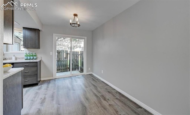 unfurnished dining area featuring an inviting chandelier and light hardwood / wood-style floors