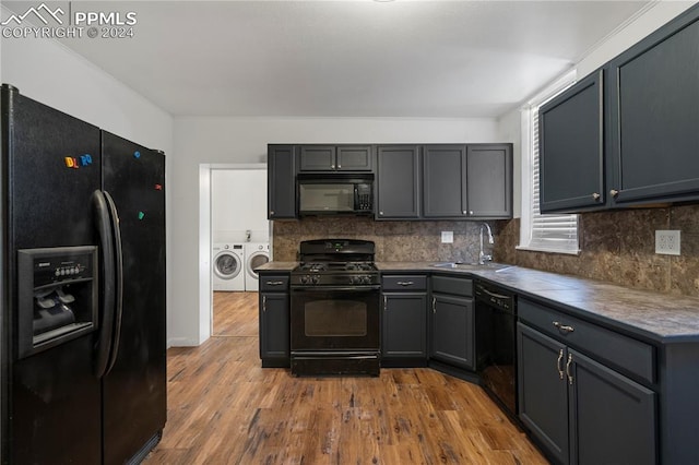 kitchen featuring gray cabinetry, black appliances, hardwood / wood-style floors, washer and dryer, and sink