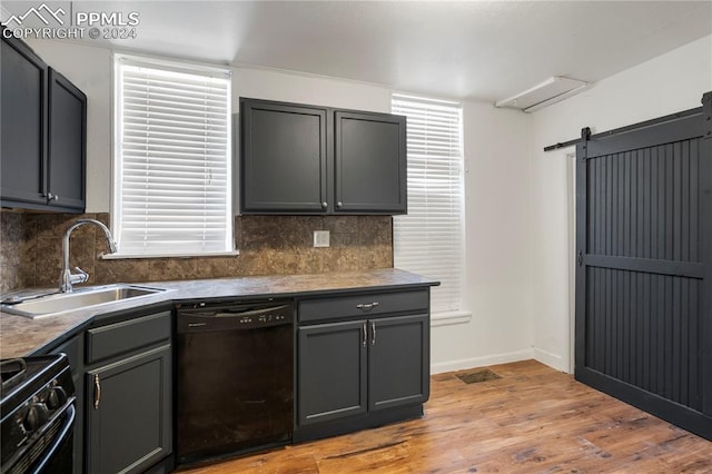 kitchen with black appliances, light hardwood / wood-style floors, sink, and a barn door