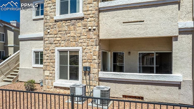 exterior space with central air condition unit, stone siding, and stucco siding