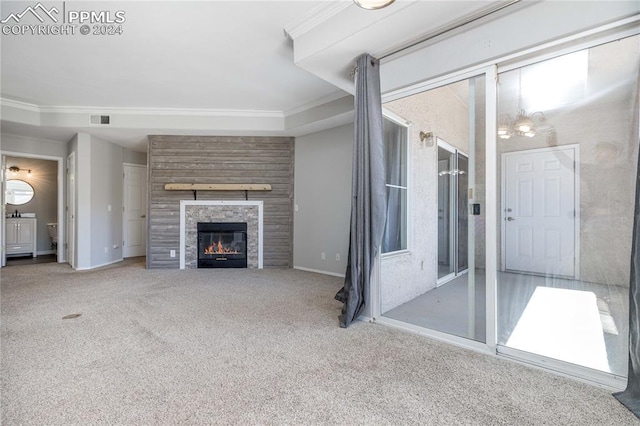 unfurnished living room with baseboards, visible vents, crown molding, carpet floors, and a fireplace