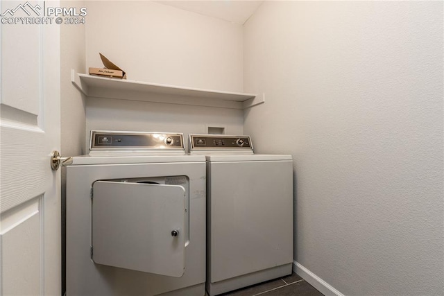 laundry area featuring dark tile patterned floors, laundry area, washer and clothes dryer, and baseboards