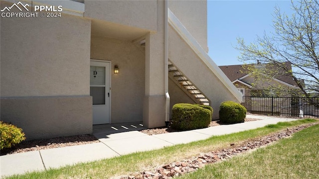 view of home's exterior with stairs, fence, and stucco siding