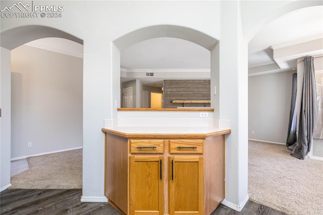 kitchen with baseboards, open floor plan, ornamental molding, tile counters, and dark colored carpet