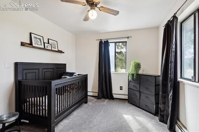 bedroom featuring ceiling fan, a baseboard heating unit, a nursery area, and carpet floors