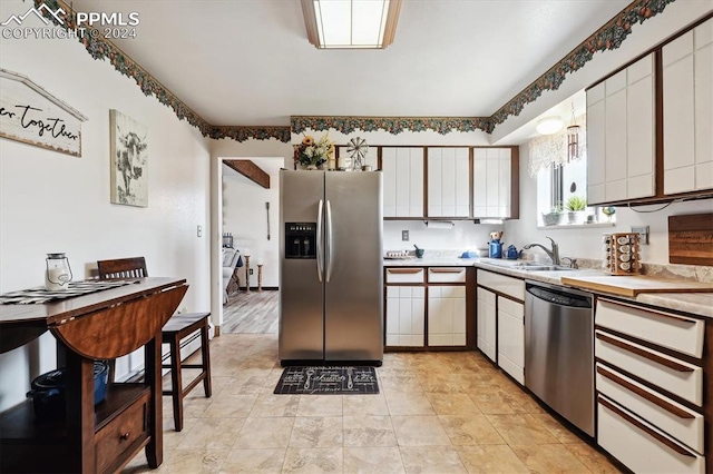 kitchen with light tile patterned flooring, sink, stainless steel appliances, and white cabinets