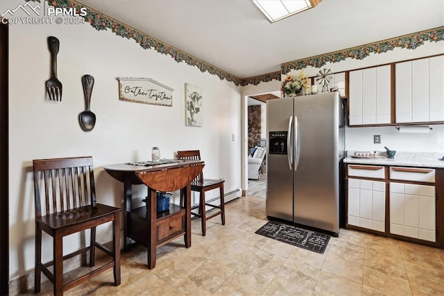 kitchen with light tile patterned floors, stainless steel fridge, a baseboard radiator, and white cabinets