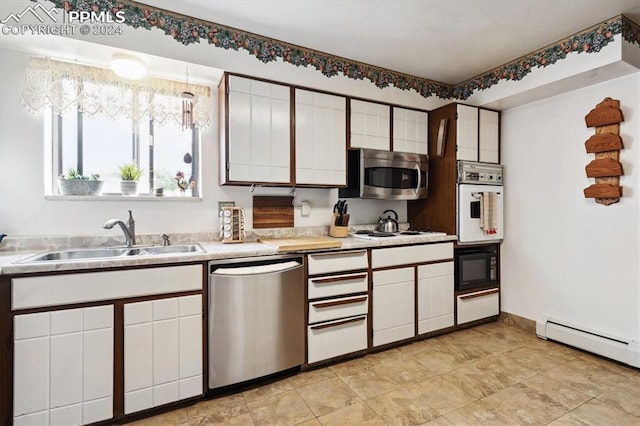 kitchen with appliances with stainless steel finishes, light tile patterned flooring, white cabinets, and sink