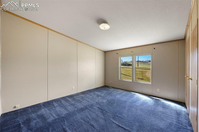 unfurnished room featuring ornamental molding, dark colored carpet, and a textured ceiling