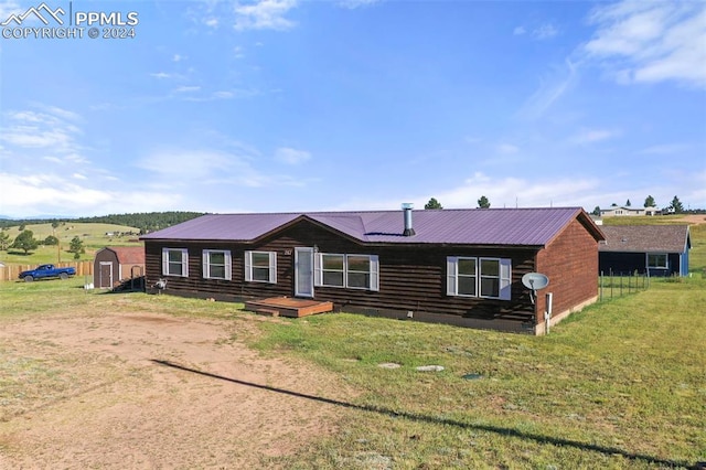 view of front of house with a storage shed, a front lawn, metal roof, and an outdoor structure