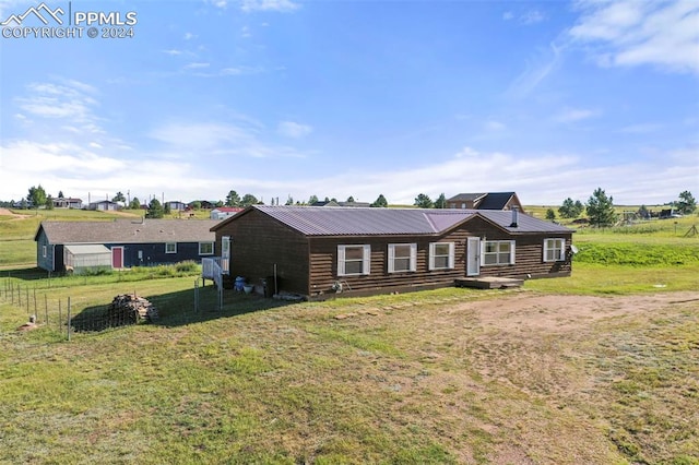 view of front of house featuring metal roof, a front lawn, and fence