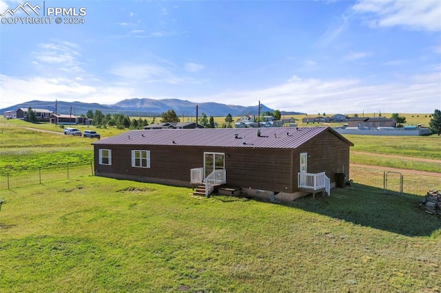 rear view of property with metal roof, a lawn, fence, and a mountain view