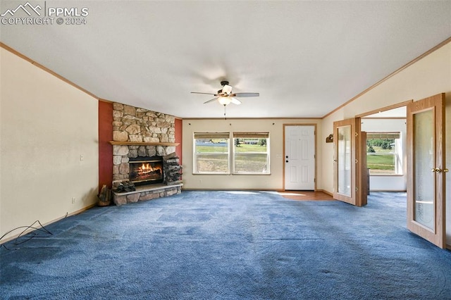 unfurnished living room with a stone fireplace, carpet flooring, a healthy amount of sunlight, and ornamental molding