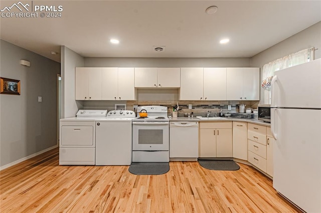 kitchen featuring washer and dryer, white cabinetry, light hardwood / wood-style floors, sink, and white appliances