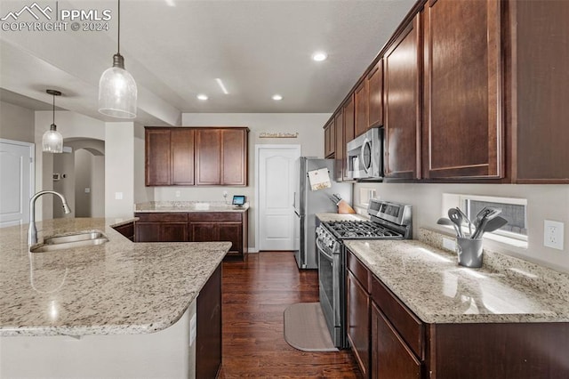 kitchen with sink, dark hardwood / wood-style flooring, appliances with stainless steel finishes, light stone countertops, and hanging light fixtures