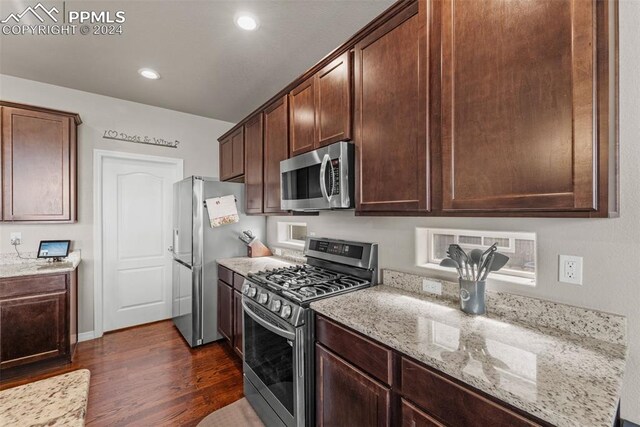 kitchen with appliances with stainless steel finishes, light stone counters, dark wood-type flooring, and dark brown cabinetry