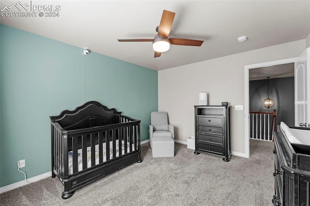 carpeted bedroom featuring ceiling fan and a crib