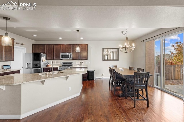 kitchen with appliances with stainless steel finishes, sink, light stone counters, and dark hardwood / wood-style flooring