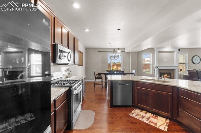 kitchen featuring sink, hanging light fixtures, light stone countertops, dark hardwood / wood-style floors, and stainless steel appliances