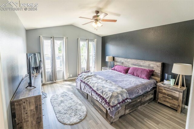 bedroom with light hardwood / wood-style floors, ceiling fan, and lofted ceiling