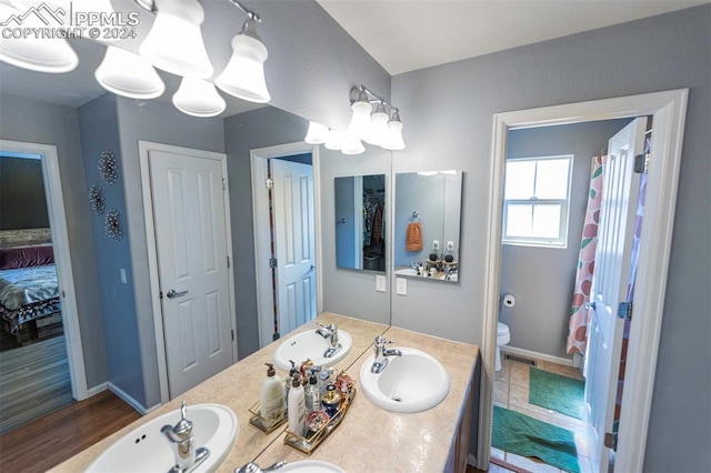 bathroom featuring toilet, hardwood / wood-style floors, and dual bowl vanity