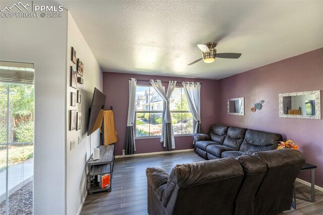 living room featuring ceiling fan, dark wood-type flooring, and a textured ceiling