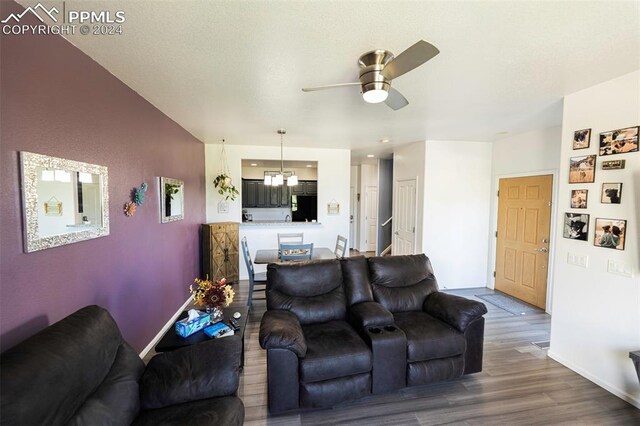 living room with ceiling fan with notable chandelier and hardwood / wood-style flooring