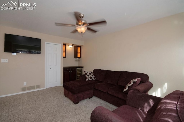 living room featuring beverage cooler, ceiling fan, and light carpet