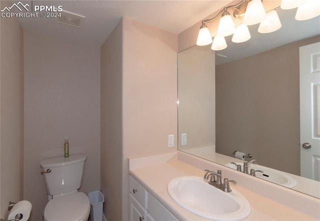 bathroom featuring toilet, an inviting chandelier, and vanity