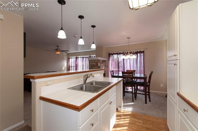 kitchen with sink, white cabinets, pendant lighting, and tile countertops