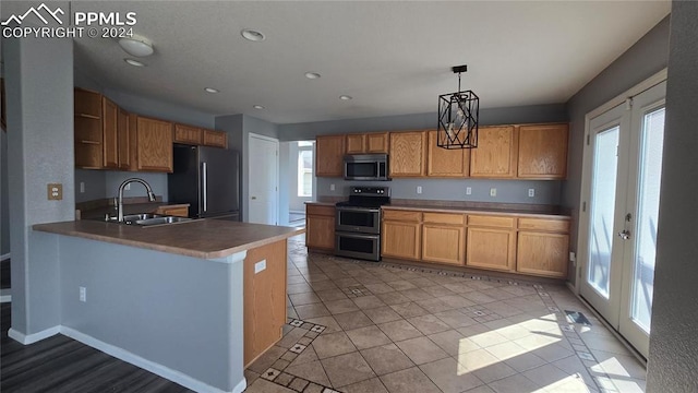 kitchen featuring french doors, kitchen peninsula, sink, decorative light fixtures, and appliances with stainless steel finishes