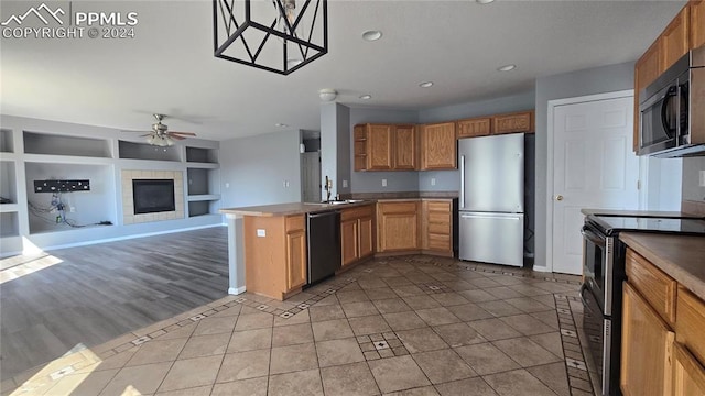 kitchen featuring appliances with stainless steel finishes, a fireplace, built in features, ceiling fan, and decorative light fixtures