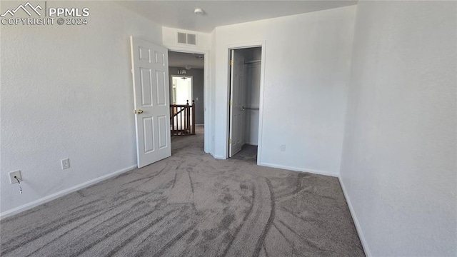 unfurnished bedroom with carpet and a walk in closet