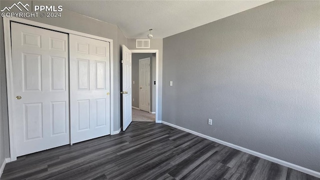 unfurnished bedroom featuring dark hardwood / wood-style floors and a closet