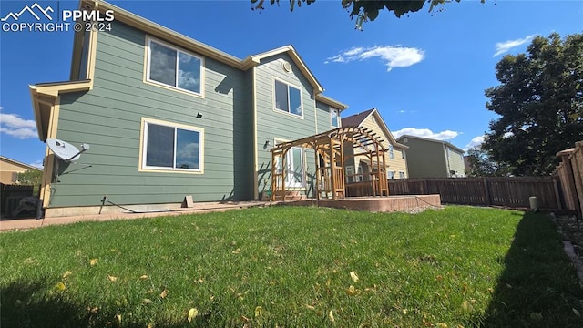 rear view of property featuring a patio area, a yard, and a pergola