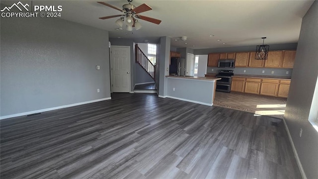 kitchen with appliances with stainless steel finishes, decorative light fixtures, ceiling fan with notable chandelier, and dark hardwood / wood-style flooring