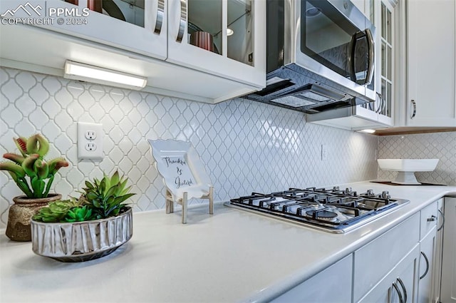 kitchen with appliances with stainless steel finishes, tasteful backsplash, and white cabinets