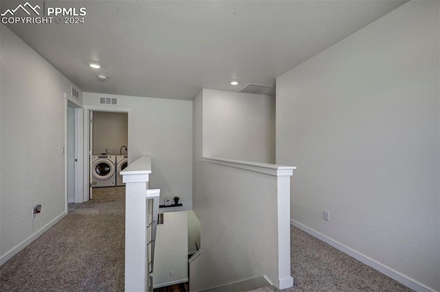 corridor featuring washing machine and dryer, carpet, visible vents, and an upstairs landing