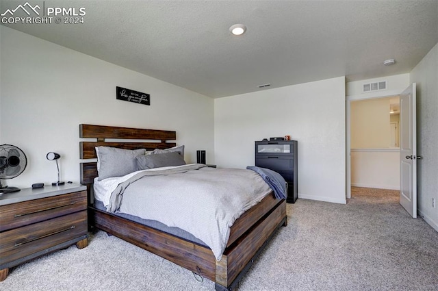 bedroom with a textured ceiling and light carpet