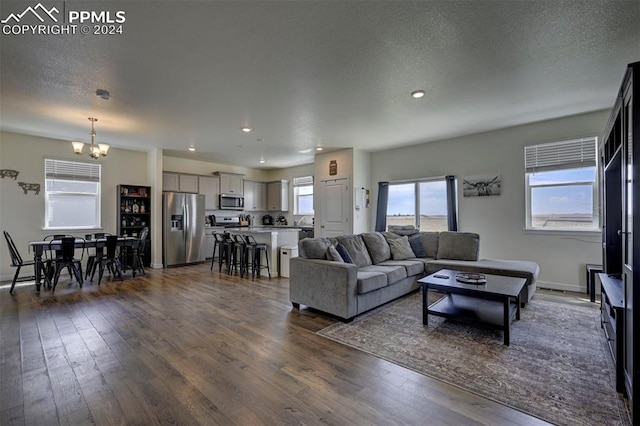 living room with dark hardwood / wood-style floors, a textured ceiling, and a chandelier