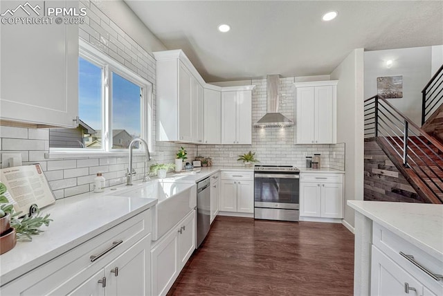 kitchen with dark wood finished floors, wall chimney exhaust hood, white cabinetry, and appliances with stainless steel finishes