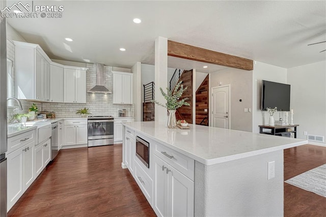 kitchen with visible vents, backsplash, dark wood-type flooring, stainless steel appliances, and wall chimney exhaust hood