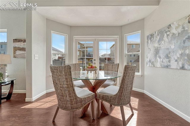 dining space with a textured wall, french doors, baseboards, and wood finished floors