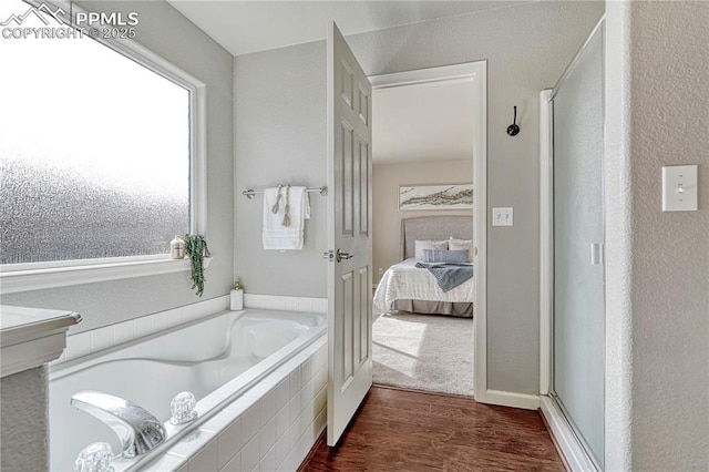 ensuite bathroom featuring a shower stall, ensuite bathroom, a garden tub, and wood finished floors